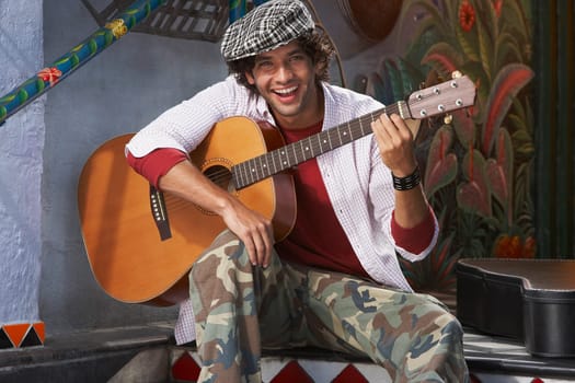 Portrait of a young man holding a guitar and smiling