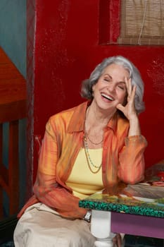 Senior woman sitting in a restaurant and laughing