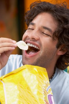 Close-up of a young man eating potato chips