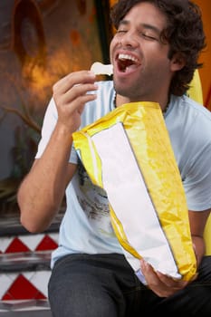 Close-up of a young man eating potato chips