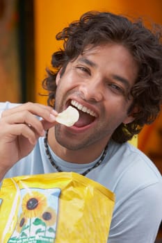 Portrait of a young man eating potato chips