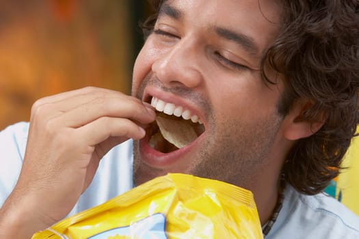 Close-up of a young man eating potato chips