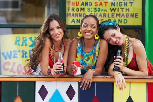 Portrait of three young women leaning on a railing and holding cold drinks
