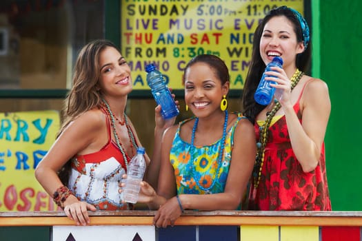 Portrait of three young women leaning on a railing and holding water bottles