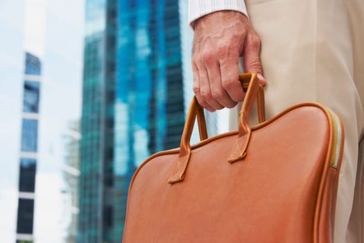 Mid section view of a businessman holding a handbag