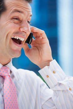 Close-up of a businessman talking on a mobile phone and laughing