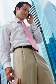 Low angle view of a businessman talking on a mobile phone and smiling