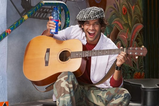 Portrait of a young man playing a guitar and holding a water bottle