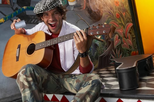 Portrait of a young man holding a guitar and a credit card