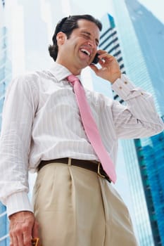 Low angle view of a businessman talking on a mobile phone and laughing