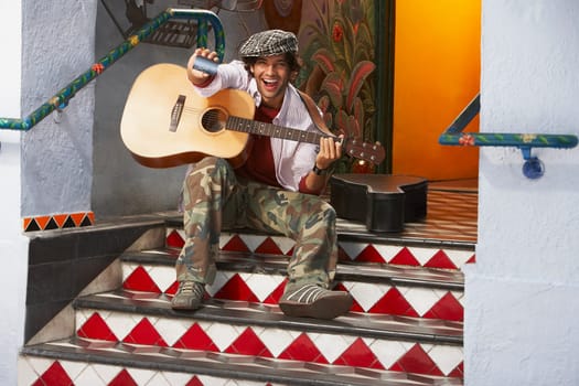 Portrait of a young man holding a guitar and a credit card