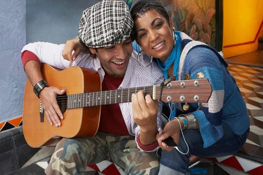 Close-up of a young man playing a guitar and smiling with a young woman