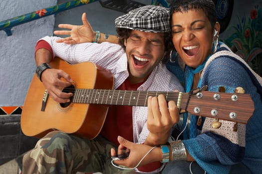 Close-up of a young man singing with a young woman and playing a guitar