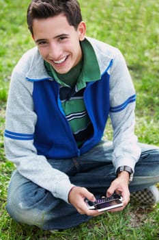 High angle view of a teenage boy smiling and using a mobile phone