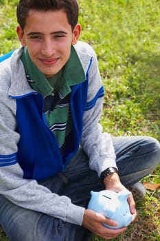 Close-up of a teenage boy holding a piggy bank