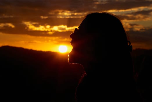 Silhouette of a woman pretending to eat sun at dusk