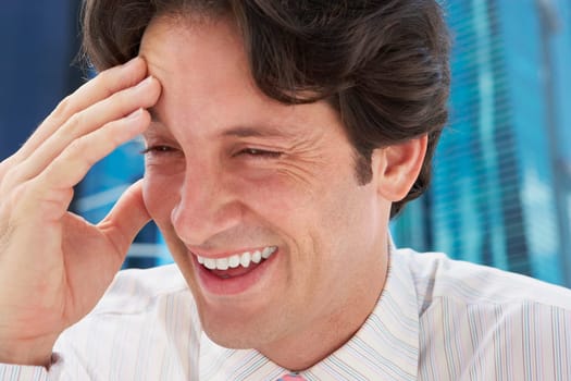 Close-up of a businessman smiling with his hand on his forehead