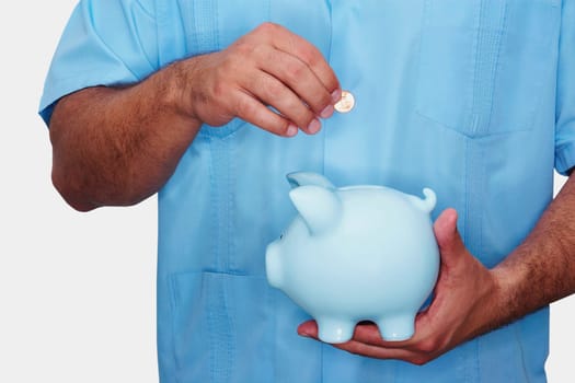 Mid section view of a male nurse inserting a gold coin into a piggy bank