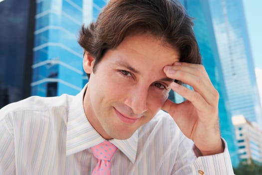 Portrait of a businessman smiling with his hand on his forehead
