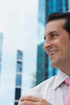 Close-up of a businessman holding a disposable cup and smiling