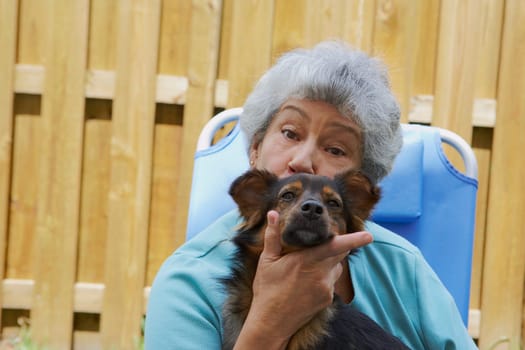 Portrait of a senior woman kissing a dog
