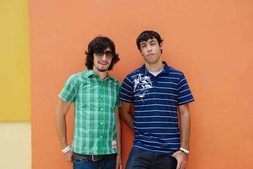 Two young men standing in front of a wall