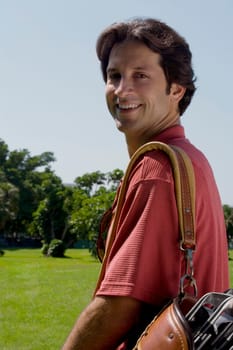 Portrait of a mid adult man carrying a golf bag and smiling