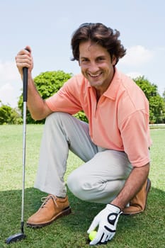 Portrait of a mid adult man holding a golf ball and a golf club