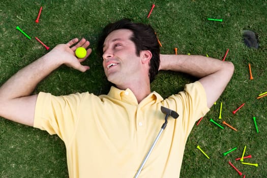 High angle view of a mid adult man lying on a golf course and looking at a golf ball