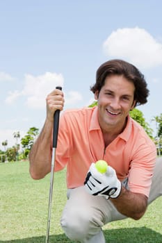Portrait of a mid adult man holding a golf ball and a golf club