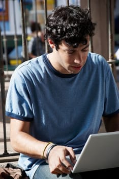 Close-up of a young man sitting and using a laptop