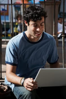 Close-up of a young man using a laptop and smiling