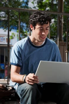 Close-up of a young man sitting and using a laptop