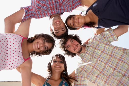 Low angle view of three young women and two young men in a huddle