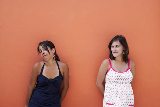 Two young women leaning against a wall