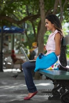 Side profile of a young woman sitting in a park and using a laptop, Old San Juan, San Juan, Puerto Rico