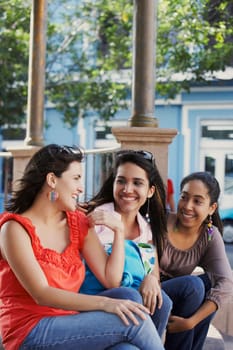 Three young women sitting together and smiling, Old San Juan, San Juan, Puerto Rico