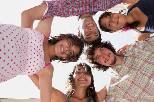 Low angle view of three young women and two young men in a huddle
