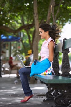 Side profile of a young woman sitting in a park and using a laptop, Old San Juan, San Juan, Puerto Rico