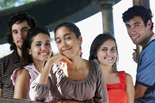 Two young men with three young women posing and smiling
