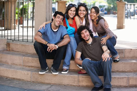 Two young men with three young women sitting on steps and smiling