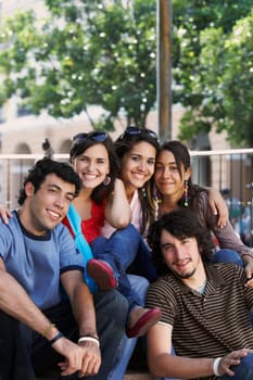 Portrait of three young women and two young men sitting together and smiling