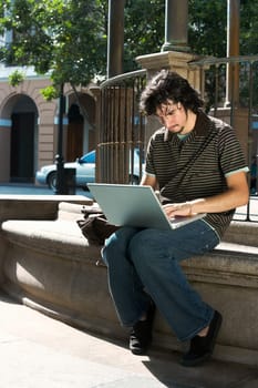 Close-up of a young man sitting and using a laptop