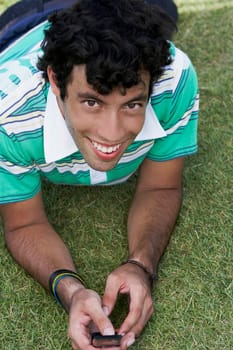 Portrait of a young man lying on front and text messaging