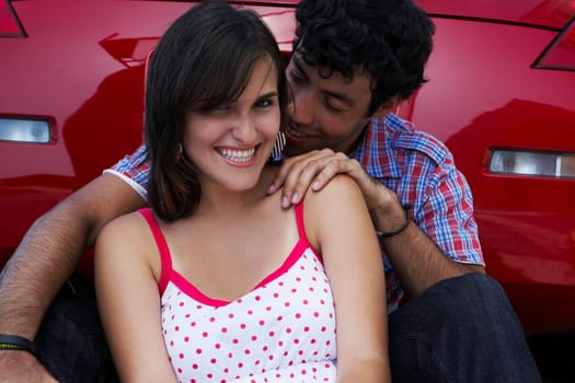 Close-up of a young couple sitting in front of a car