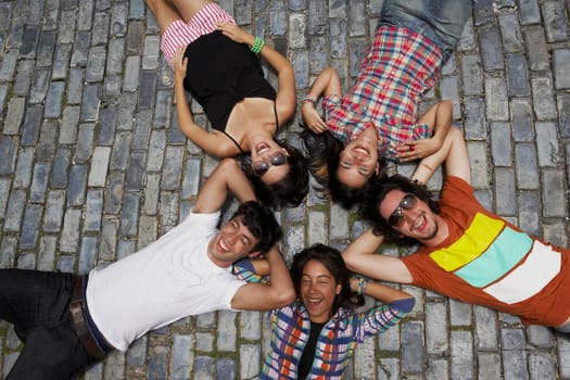 High angle view of three young women with two young men lying on cobblestone and smiling, Old San Juan, San Juan, Puerto Rico