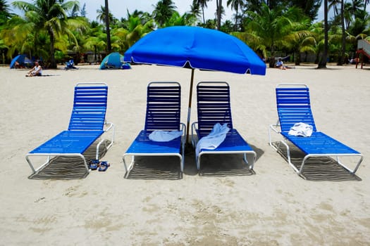 Lounge chairs under a beach umbrella on the beach, Luquillo Beach, Puerto Rico