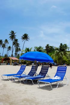 Lounge chairs under a beach umbrella on the beach, Luquillo Beach, Puerto Rico