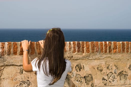 Rear view of a young woman looking over a castle wall, Morro Castle, Old San Juan, San Juan, Puerto Rico