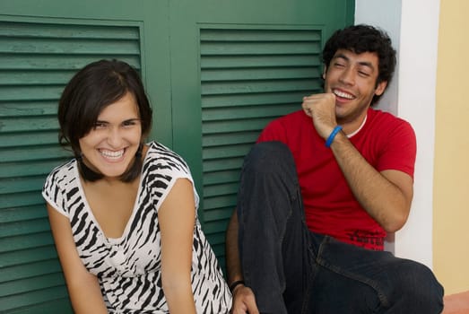 Portrait of a young woman smiling with a young man sitting beside her and coughing
